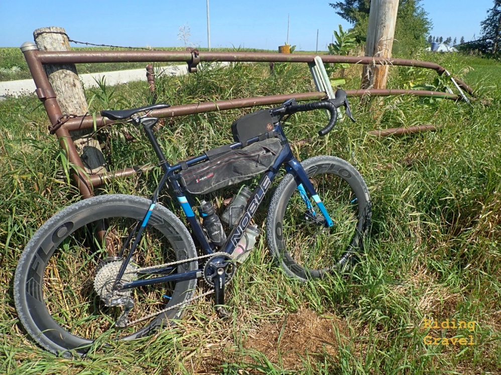 A bicycle leaning against a gate on a rural road