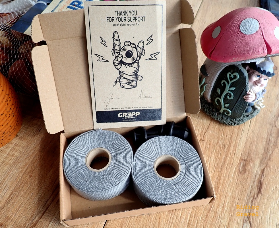 An open box of Grepp handle bar tape on a table with other objects