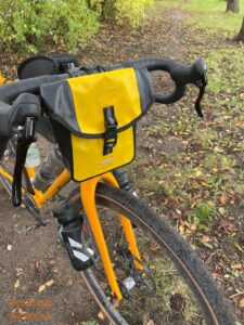 The Craft Cadence Handle Bar Bag on a bicycle in a wooded area.