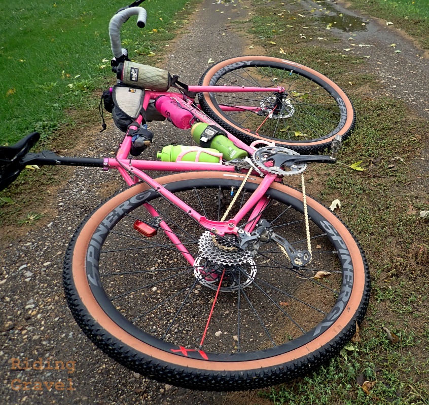 A pink bicycle laying down on a two-track dirt/gravel road with the American Classic Wentworth tires mounted. 