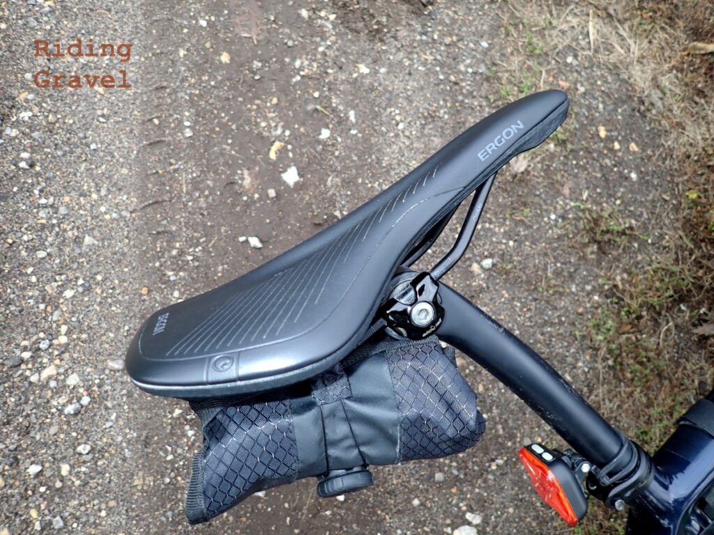 The Ergon SR Allroad Core Comp saddle in a close up view against a gravel/dirt road
