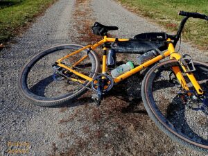 A bike laying on its side on a two track gravel road. 