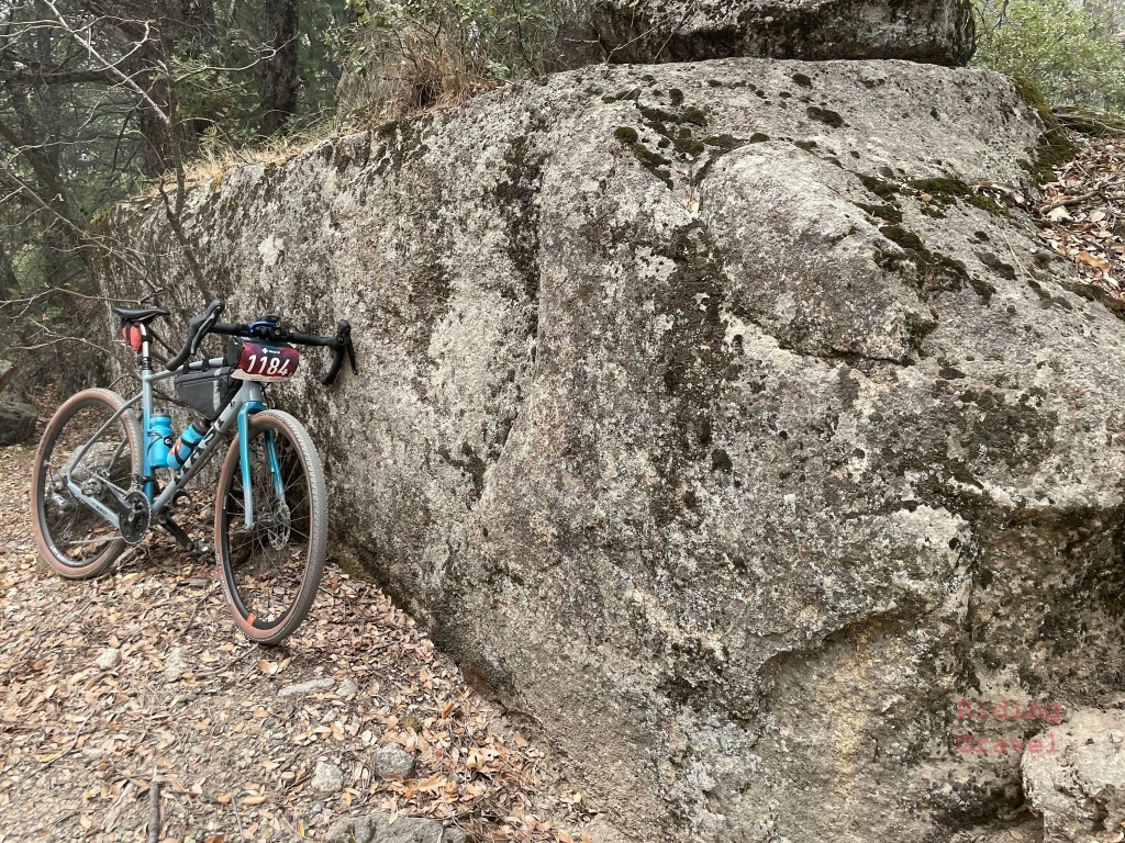 A bicycle leaning against a boulder in a rural setting