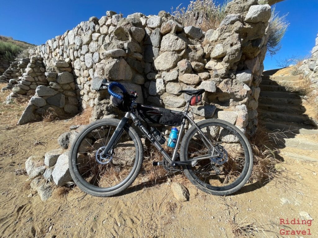 A bicycle leaned up against stone ruins in a rural setting