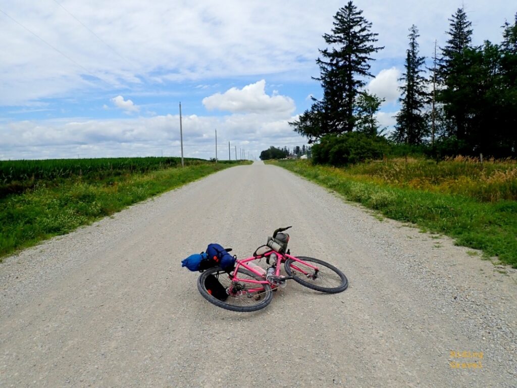 A bicycle loaded with bags on a gravel road in a rural area. OMM Elkhorn rack used here. 