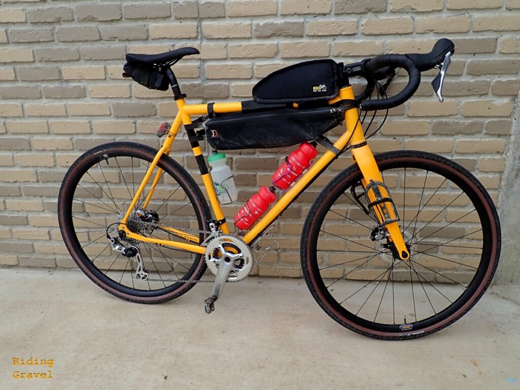 Image of a yellow bike against a brick wall.