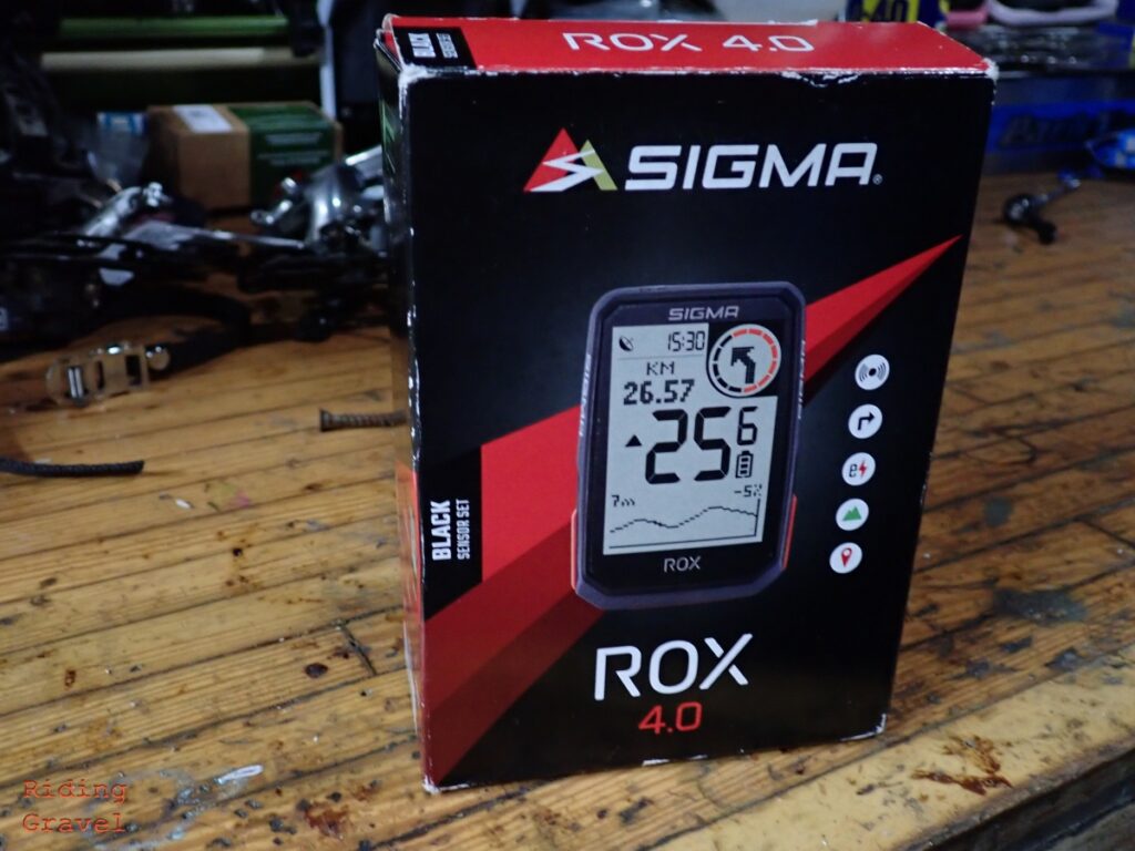 The SIGMA ROX 4.0 GPS Cycling computer in the box on a bench top