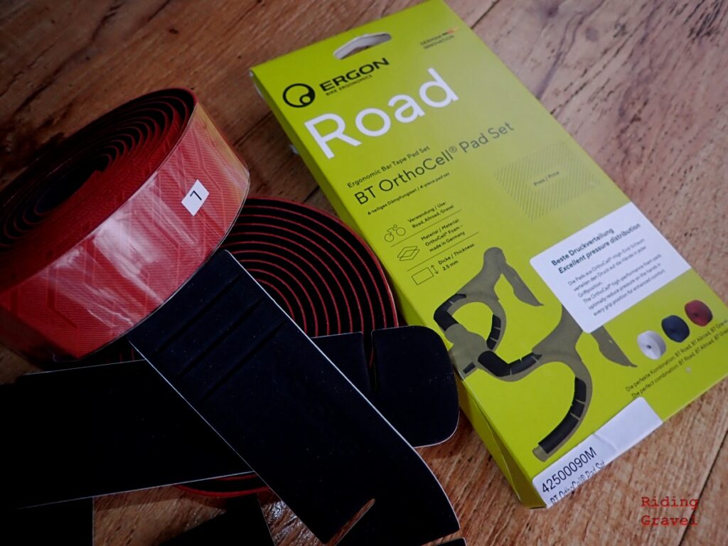 Shot of the Ergon BT OrthoCell Handlebar Pad Set, BT Gravel Tape, and packaging on a table. 