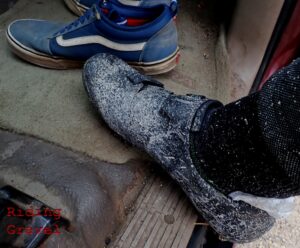 Detail shot of some dirty cycling shoes and some Vans shoes in the interior of an automobile. 
