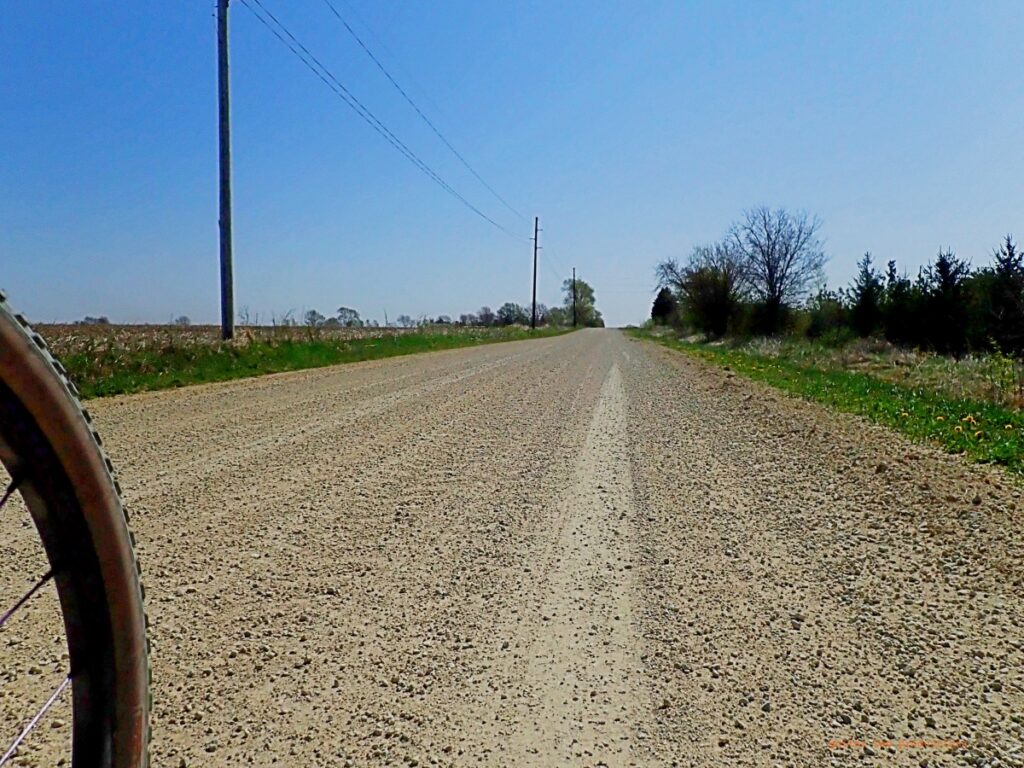 View of a bicycle tire and a crushed rock road in a rural area. 