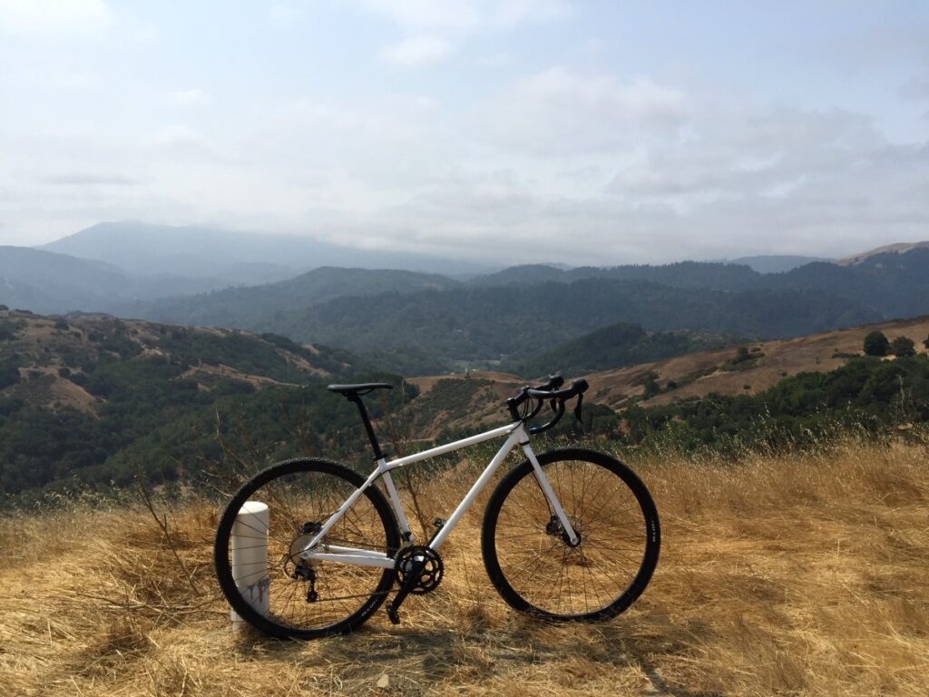 Image of a white bicycle in a mountainous region featuring 750D wheels and tires. 