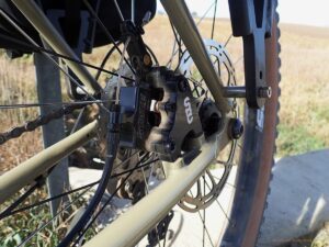 Close-up of a rear disc brake caliper on a bike in a rural setting.